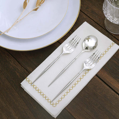 Elegant silver cutlery set on a white napkin with decorative embroidery.