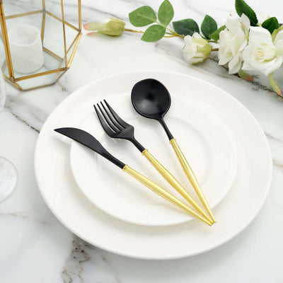 Elegant black and gold cutlery set on a white plate with marble background.