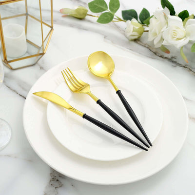 Gold and black cutlery set on a white plate, elegant dining table setting.