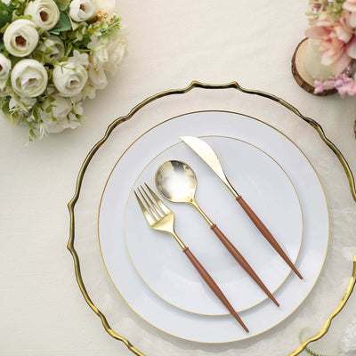 Elegant table setting with gold-accented plates and wooden-handled cutlery.