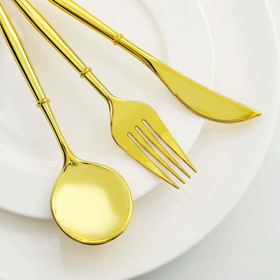 Gold cutlery set including spoon, fork, and knife on a white plate.