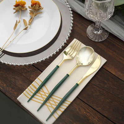 Elegant gold cutlery set with green handles on a stylish table setting.