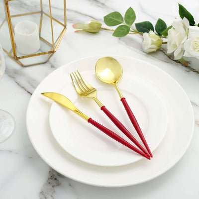 Gold cutlery set with red handles on a white plate