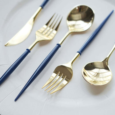 Gold cutlery set with blue handles on a white plate.