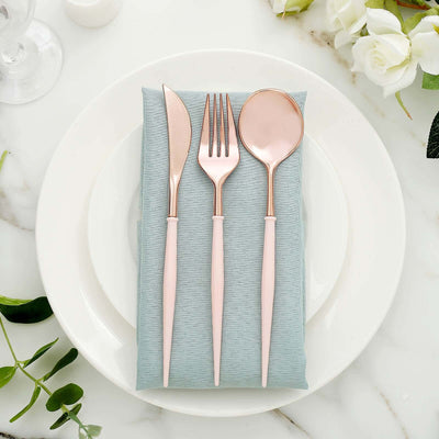 Rose gold cutlery set on a light blue napkin atop a white plate
