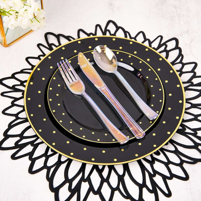 Black and gold dotted dinner plate set with utensils on a decorative placemat.