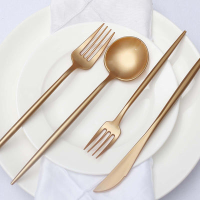 Gold cutlery set on white plate with napkin.