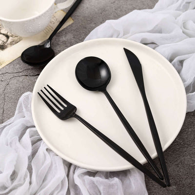 Black cutlery set on a white plate with a textured background.