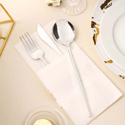 Silver cutlery set on a cream napkin for elegant dining.