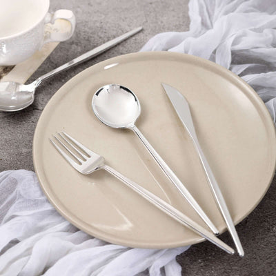 Silver cutlery set on a beige plate with a textured backdrop.