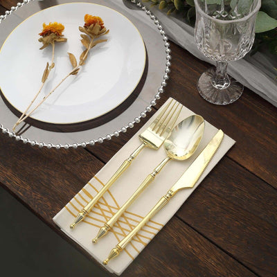 Elegant gold cutlery set with plate and decorative napkin on a wooden table.