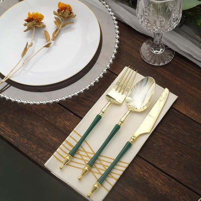 Elegant gold and green cutlery set on a stylish table setting.