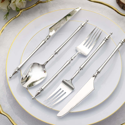 Silver cutlery set on an elegant plate with gold trim.