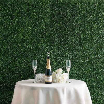 Champagne bottle and glasses on a table with floral decor against a greenery backdrop.
