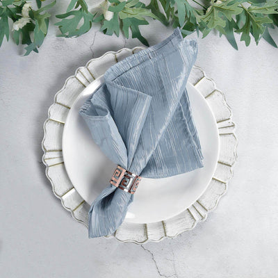 Blue textured napkin on a decorative white plate with a napkin ring.