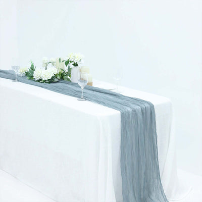Elegant gray table runner with floral arrangement and glasses on a white table.