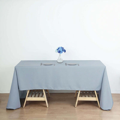 Grey tablecloth draped over a wooden table with a floral centerpiece.
