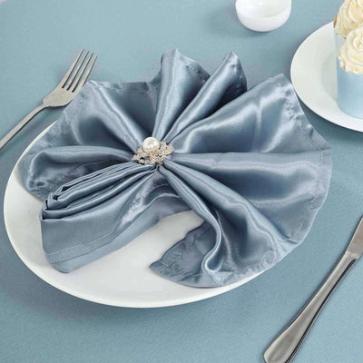 Elegant blue satin napkin with pearl detail on a plate.