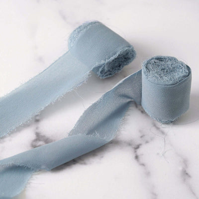 Light blue fabric ribbon rolls on a marble surface.