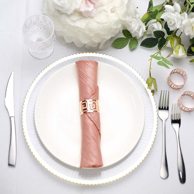 Elegant table setting with a pink napkin and gold napkin ring on a white plate.