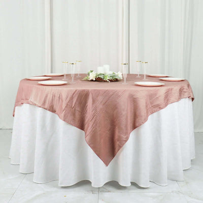 Round table set with a blush tablecloth and white plates.