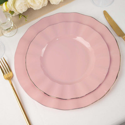 Pink scalloped dinner plates with gold trim on a table setting.