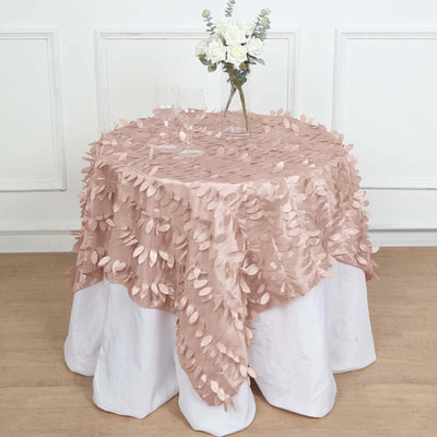 Pink leaf-pattern tablecloth draped over a round table with a floral centerpiece.