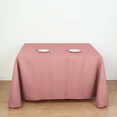 Pink tablecloth draped over a dining table with plates and utensils.