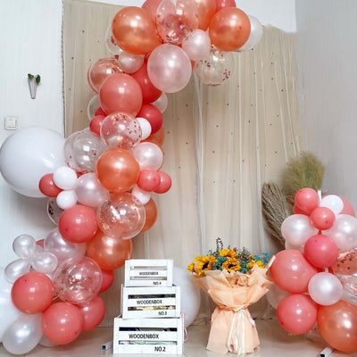 Balloon arch with floral arrangement and decorative boxes in a festive setup.