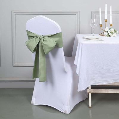 White chair cover with green bow in an elegant dining setup.