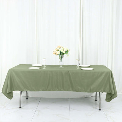 Olive green tablecloth draped over a table with plates and flowers