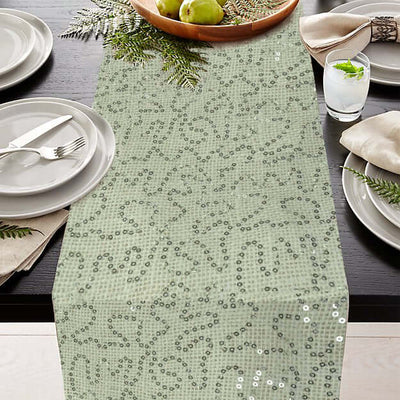 Green sequined table runner on a dining table with plates and decor.