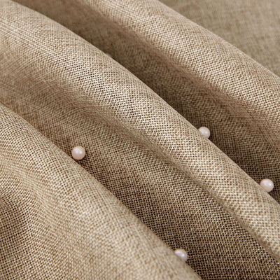 Textured beige fabric with pearl accents, showcasing intricate detail.