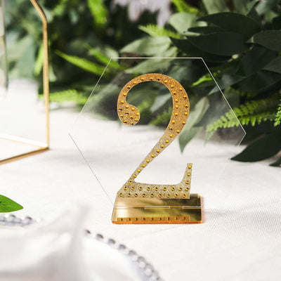 Gold glitter number 2 table centerpiece on a clear hexagonal base.