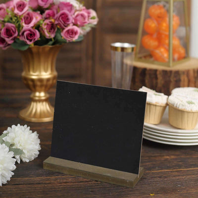 Black tabletop sign holder with a gold base, surrounded by floral decor and treats.