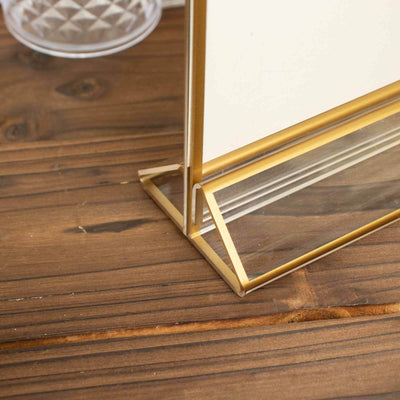 Gold metal photo frame base on a wooden surface.