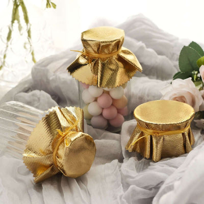 Gold foil party favor jars with colorful candy inside.