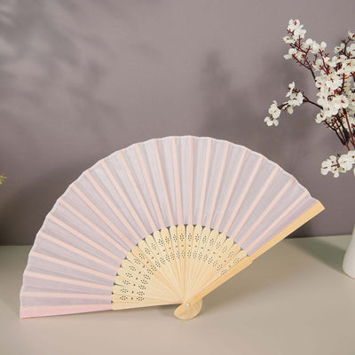 Decorative pink and white folding fan against a soft purple background.