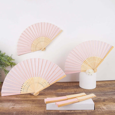 Pink folding fans displayed on a table with a minimalistic backdrop.