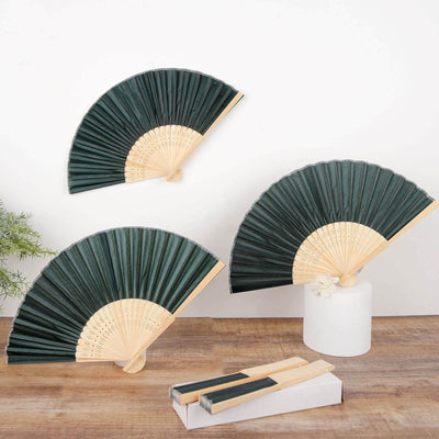 Green folding fans with bamboo handles on a wooden surface.