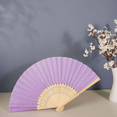 Purple decorative fan displayed next to a vase with flowers.