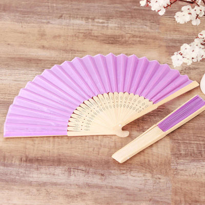 Purple folding fan displayed on a wooden surface.