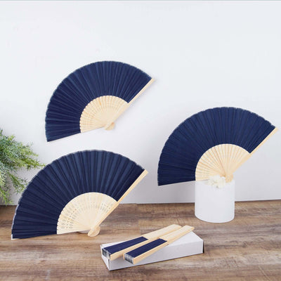 Navy folding fans with bamboo handles displayed on a wooden surface.