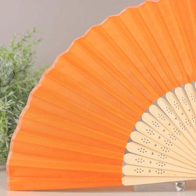 Orange folding fan with decorative cutouts on wooden handle.