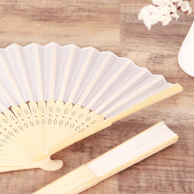 Elegant folding fan with bamboo handle on wooden surface.