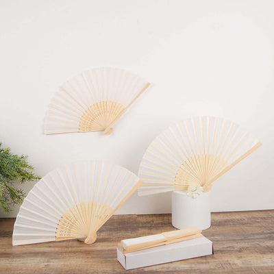 Set of three elegant white bamboo fans on a wooden surface.