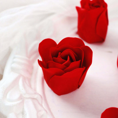 Red artificial rose on a decorative white surface.