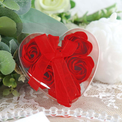 Red rose gift box in heart shape with a ribbon, surrounded by greenery.