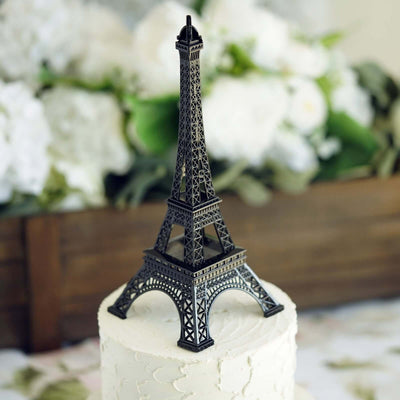 Eiffel Tower cake topper on a decorated cake with floral background.