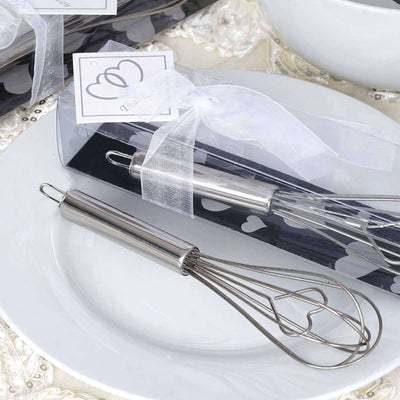 Heart-shaped whisk in elegant packaging on a decorative plate.